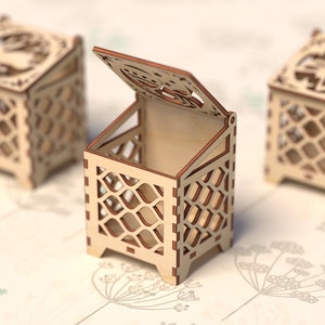 May include: Three wooden boxes with intricate cut-out designs. The box in the center is open, revealing the empty interior. The boxes are made of light brown wood and have a delicate, lacy appearance.