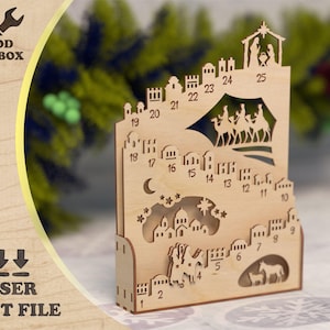 Op de afbeelding: Lasergesneden houten adventskalender met een kerststal en genummerde dagen. De kalender heeft uitgesneden ontwerpen van gebouwen, sterren en kamelen, met de tekst "WOOD TOOLBOX" en "LASER CUT FILE".