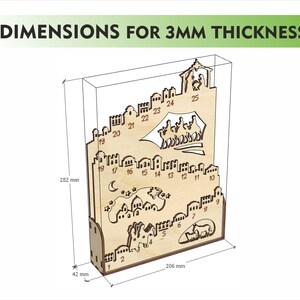 Op de afbeelding: Houten adventskalender met lasergesneden stad- en kerststalontwerpen. De kalender is 28,2 cm hoog, 20,6 cm breed en 4,2 cm diep. De tekst "DIMENSIONS FOR 3MM THICKNESS" staat bovenaan.