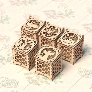 May include: Five wooden boxes with intricate laser cut designs. Each box features a different design, including a bunny, a flower, an angel, and an Easter egg. The boxes are all made of natural wood and have a light brown color.