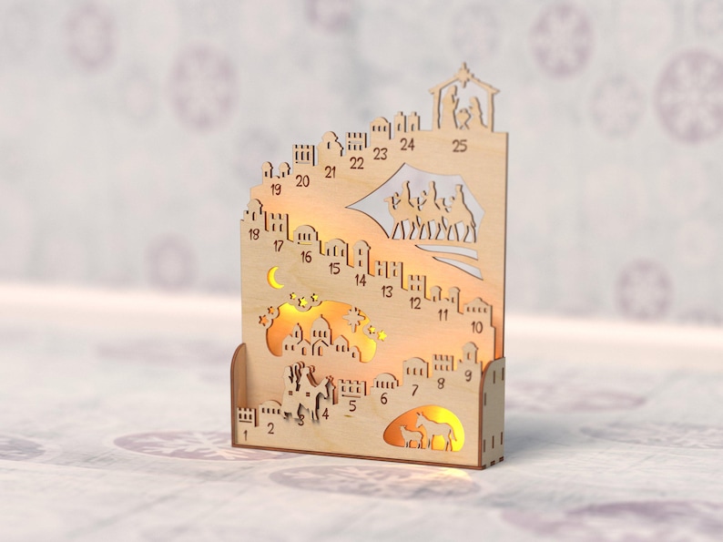 Op de afbeelding: Houten adventskalender met een stadsgezicht, uitgesneden ontwerpen en de nummers 1-25. De kalender heeft een halve maan, sterren en verlichte figuren. Het algehele ontwerp is lichtbruin.