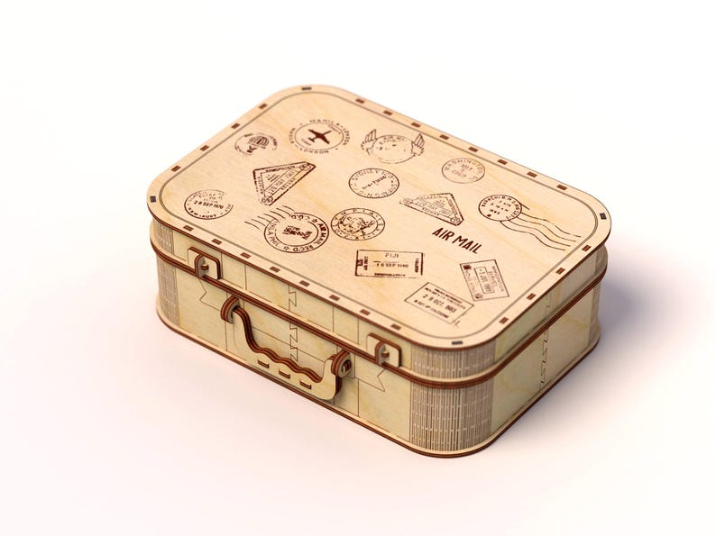 Puede incluir: Una maleta de madera de color claro con un asa y varios sellos con tem&aacute;tica de viajes y las palabras "AIR MAIL" impresas en la parte superior. La maleta es rectangular con esquinas redondeadas y un asa marr&oacute;n.