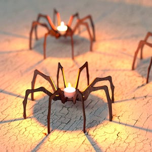 Peut inclure: Trois bougeoirs en forme d'araign&eacute;e en m&eacute;tal marron avec des bougies blanches allum&eacute;es. Les bougeoirs sont sur une surface textur&eacute;e blanc cass&eacute;, projetant des ombres. Les flammes des bougies brillent.