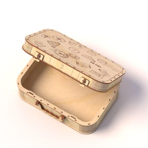 Puede incluir: Una caja de madera con forma de maleta vintage, con la tapa ligeramente abierta. La caja es de madera clara y presenta sellos grabados con tem&aacute;tica de viaje y las palabras "AIR MAIL" en la tapa. Tiene un asa peque&ntilde;a y cierres met&aacute;licos.