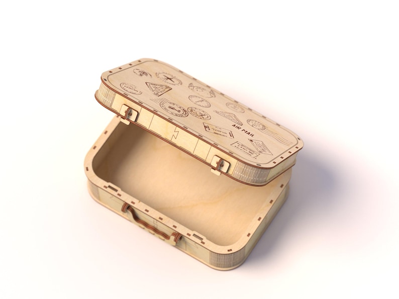 Puede incluir: Una caja de madera con forma de maleta vintage, con la tapa ligeramente abierta. La caja es de madera clara y presenta sellos grabados con tem&aacute;tica de viaje y las palabras "AIR MAIL" en la tapa. Tiene un asa peque&ntilde;a y cierres met&aacute;licos.
