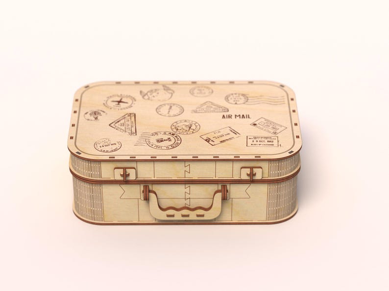Puede incluir: Una maleta de madera clara con asa y cierres. La parte superior de la maleta est&aacute; decorada con varios sellos y las palabras "AIR MAIL". La maleta rectangular parece estar hecha de madera en capas.
