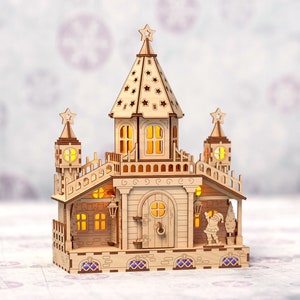 May include: A wooden Christmas village scene with a light-up castle, a Santa Claus figurine, and a Christmas tree. The castle has a pointed roof with a star on top and windows with glowing lights. The scene is made of wood and has a rustic, handcrafted look.