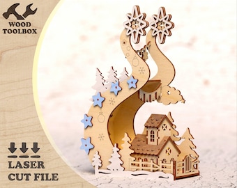 Könnte beinhalten: Ein Weihnachtsornament aus Holz, das mit einem Laser geschnitten wurde und ein Haus mit einem schneebedeckten Dach und einem gewundenen Weg, der zu ihm führt, zeigt. Das Ornament ist mit blauen Schneeflocken und Sternen verziert.