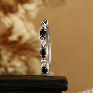 May include: A delicate silver band ring with alternating black and white oval-shaped gemstones.