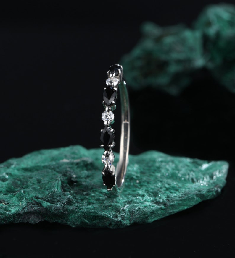 May include: A silver ring with alternating black and white oval-shaped gemstones.