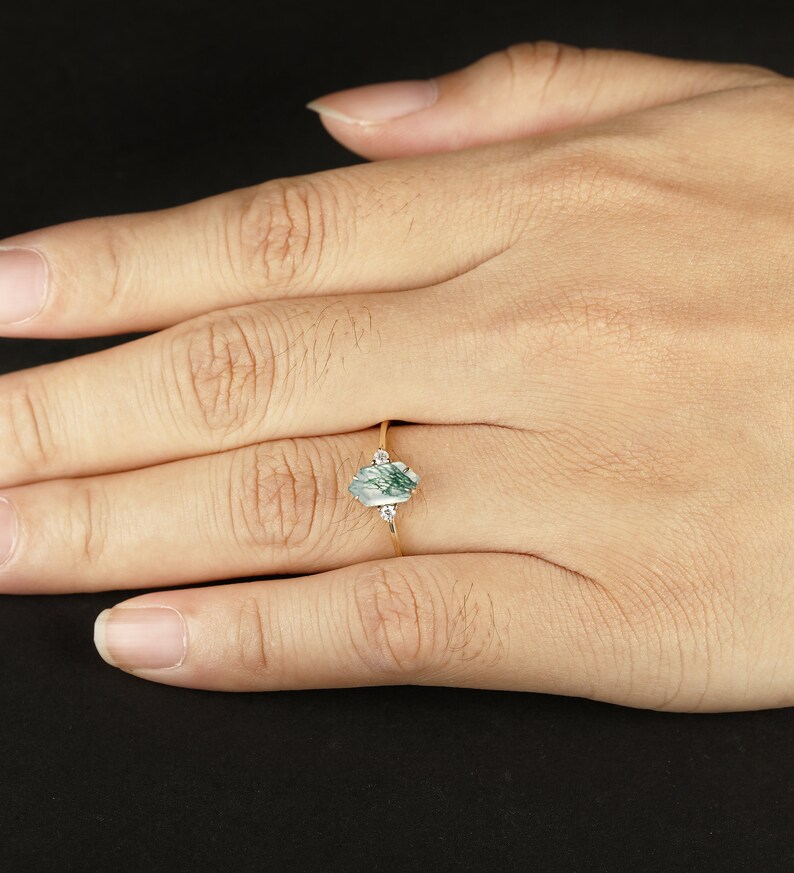 Pu&ograve; includere: Un anello d'oro con una pietra di agata verde e bianca e due piccoli diamanti sulla fascia.