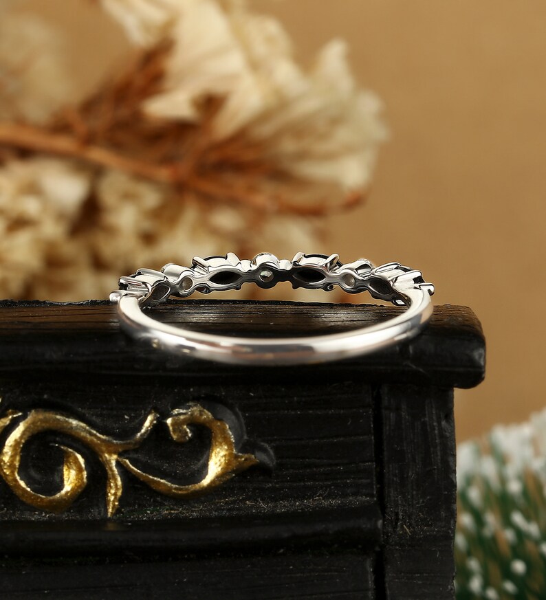 May include: A silver band ring with a row of small, clear gemstones set in a prong setting.