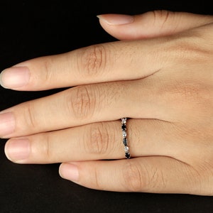 May include: A silver band ring with alternating black and white oval-shaped stones.