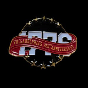 May include: A circular metal pin featuring a black background with gold stars along the perimeter. Large white numbers 1776 are centered behind a red ribbon banner with gold text reading PHILADELPHIA'S 250TH ANNIVERSARY in capital letters.