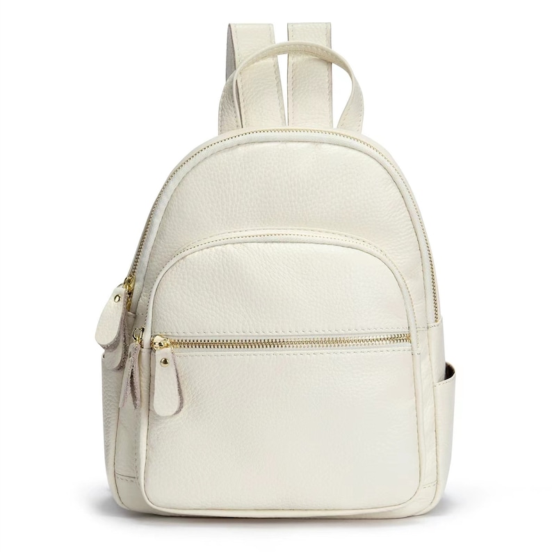 May include: A white leather backpack with gold zippers and a small pocket on the front.
