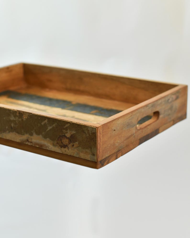 May include: A rectangular wooden serving tray with a distressed finish. The tray has a natural wood color with a dark blue and green accent in the center. It features built-in handles for easy carrying.