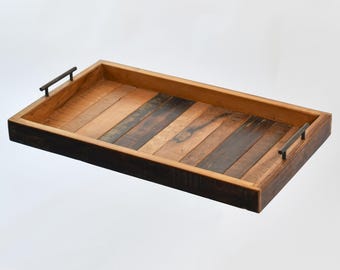 May include: A rectangular wooden tray with a dark brown wood frame and a light brown wood interior. The tray has two metal handles on the sides.