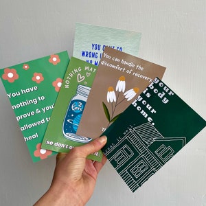 May include: Four green, white, and brown cards with inspirational quotes about self-care and healing. The quotes include "You have nothing to prove & you're allowed to heal", "Nothing matters more than your body is your home", "You can handle the discomfort of recovery", and "Treat it well".