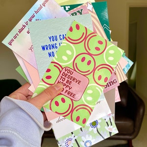 May include: A stack of colorful cards with positive affirmations and smiley faces. The cards feature phrases like "You Can't Be Wrong" and "You Deserve to Be Happy and Free".
