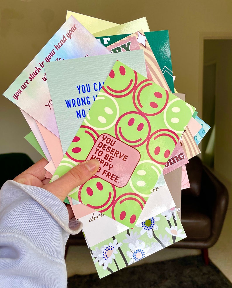 May include: A stack of colorful cards with positive affirmations and smiley faces. The cards feature phrases like "You Can't Be Wrong" and "You Deserve to Be Happy and Free".