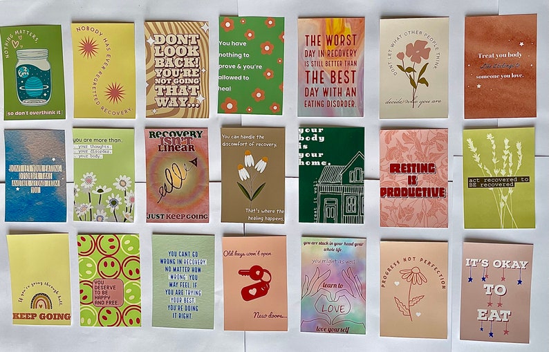 May include: A set of 16 colorful cards with encouraging messages for people in recovery. The cards feature illustrations of flowers, houses, and other designs. The text on the cards includes phrases like "Recovery is not linear", "Resting is productive", and "It's okay to eat".
