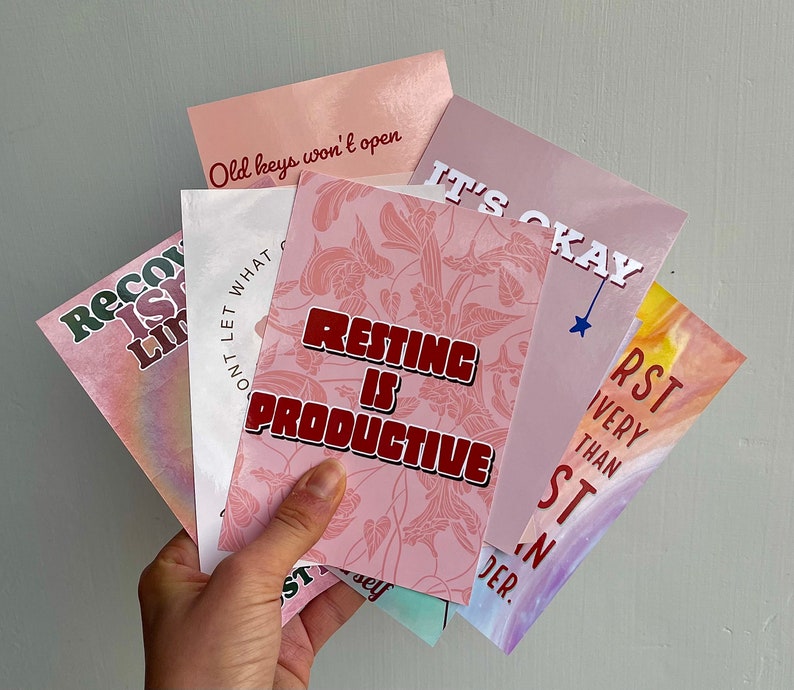May include: Five pink and white cards with inspirational quotes. The quotes are "Old keys won't open", "Resting is Productive", "It's Okay", "Don't Let What Limits You", and "First is Very Than Second".