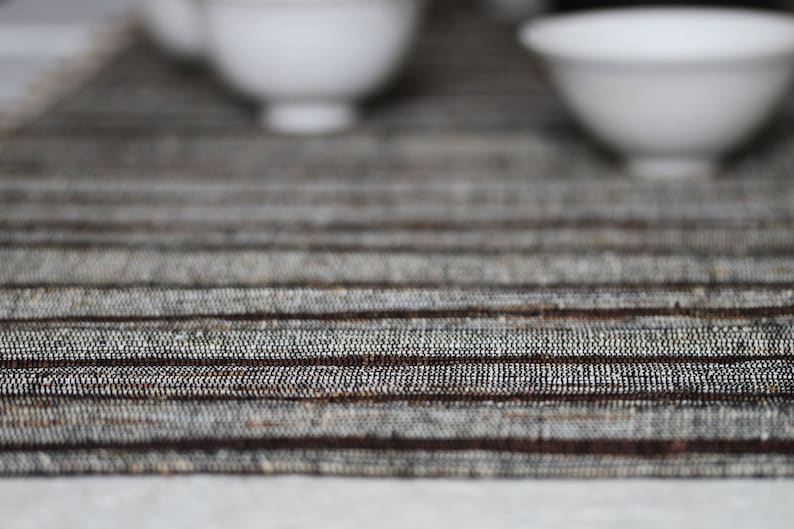 Pode incluir: Um close-up de um  placemat tecido em listras marrons e brancas. O placemat tem um brilho sutil e uma superf&iacute;cie texturizada.