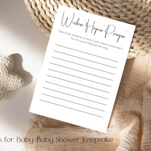Pode incluir: Um cart&atilde;o branco com texto preto que diz "Wishin' Hopin' Prayin'" e "Take a few moments to share your hopes and prayers for the sweet baby on the way." O cart&atilde;o tem linhas para escrever. O cart&atilde;o est&aacute; sobre um fundo de tecido bege.