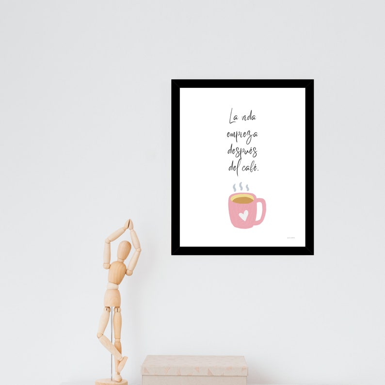 Op de afbeelding: Een zwart ingelijst print met een witte achtergrond en een roze koffiekopje met een hart erop. De tekst op de print luidt "La vida empieza despues del cafe."