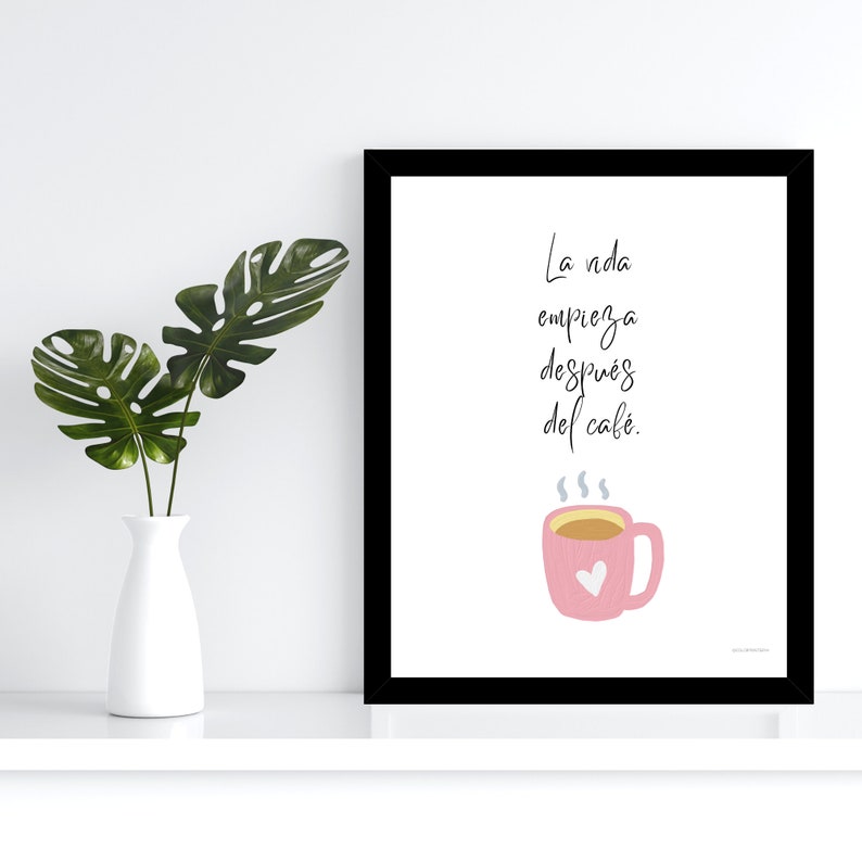 Op de afbeelding: Een zwart ingelijst print met een witte achtergrond en een roze koffiekopje met een hart erop. De tekst luidt "La vida empieza despu&eacute;s del caf&eacute;."