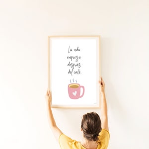 Op de afbeelding: Een ingelijst print met een roze koffiekopje en de tekst "La vida empieza despu&eacute;s del caf&eacute;." in het Spaans, wat "Het leven begint na de koffie." betekent.