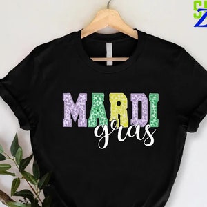 May include: Black t-shirt with the words "Mardi Gras" in green, yellow, and purple letters with a leopard print pattern.