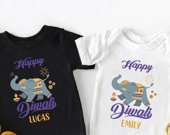 Pode incluir: Duas camisas de bebê com um design de elefante fofo e o texto "Happy Diwali". Uma camisa é preta com o nome "Lucas" e a outra é branca com o nome "Emily".