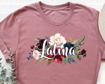 May include: A heather mauve t-shirt with a floral design and the word "Latina" in a stylized font.
