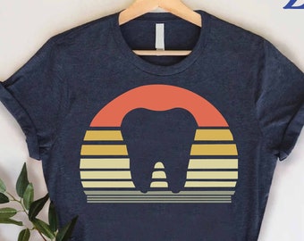 May include: A navy blue t-shirt with a vintage sunset graphic featuring a tooth in the centre. The graphic has a red, orange, yellow, and grey colour scheme. The text "CUSTOM SHIRTS Zone" is in the top right corner of the image.