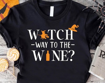 May include: Black t-shirt with white text that reads "Witch Way to the Wine?" with a witch and wine bottle graphic.