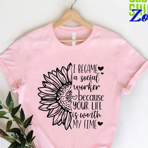 May include: Pink t-shirt with a black sunflower graphic and the text "I became a social worker because your life is worth my time".