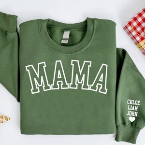 Puede incluir: Sudadera verde con la palabra "MAMA" en letras blancas en la parte delantera. La manga tiene los nombres "CHLOE, LIAM, JOHN" y un peque&ntilde;o coraz&oacute;n impreso en blanco.