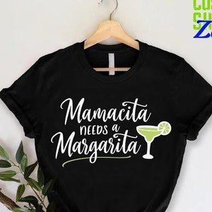 May include: Black t-shirt with white text that reads "Mamacita needs a Margarita" and a green margarita glass with a lime wedge.