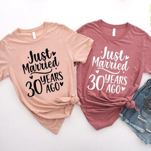 May include: Two short-sleeved t-shirts, one blush pink and one mauve, with the text "Just Married 30 Years Ago" in a black script font. The shirts are paired with denim shorts. The image also includes the text "CUSTOM SHIRTS Zone".