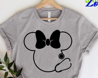 May include: A grey t-shirt featuring a black silhouette of Mickey Mouse wearing a stethoscope and a bow. The text "CUSTOM SHIRTS Zone" is in the top right corner of the image.