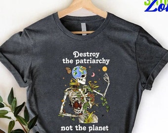 May include: Dark gray t-shirt with a skeleton holding the Earth, surrounded by vines and flowers. The text "Destroy the patriarchy not the planet" is printed on the shirt.