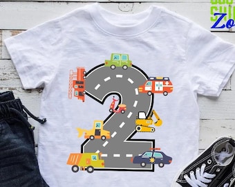 May include: White t-shirt with a gray number two on it. The number two is made of a road with various vehicles driving on it. The vehicles include a fire truck, a police car, a construction truck, a dump truck, and a scooter. The text "CUSTOM SHIRTS ZONE" is in the top right corner of the image.