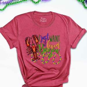 May include: A red t-shirt with a graphic of a crawfish and the text "I just want to be loved in the Bayou".
