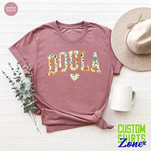 a t - shirt with the word doula on it next to a hat and