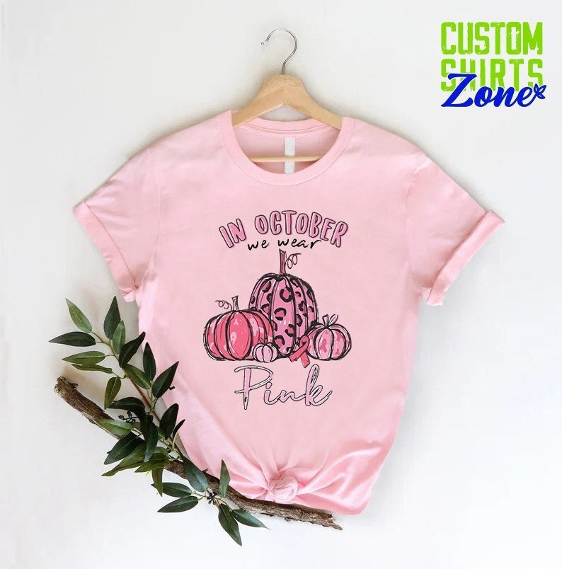 May include: Pink t-shirt with a graphic of pink pumpkins with a pink ribbon and the text "In October we wear Pink".
