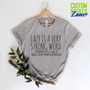 May include: Gray t-shirt with the text "LAZY IS A VERY STRONG WORD I PREFER TO CALL IT SELECTIVE PARTICIPATION" printed on it.