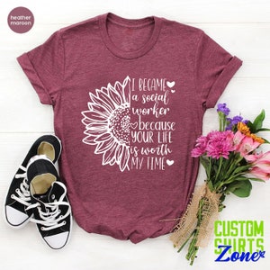 May include: A heather maroon t-shirt with a white sunflower graphic and the text "I became a social worker because your life is worth my time".