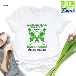 May include: White t-shirt with green text and a green butterfly graphic. The text reads "Cerebral Palsy is not contagious (but my smile is)".