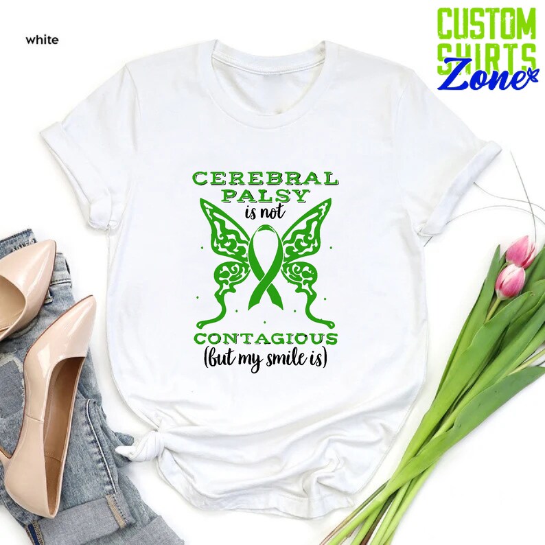 May include: White t-shirt with green text and a green butterfly graphic. The text reads "Cerebral Palsy is not contagious (but my smile is)".